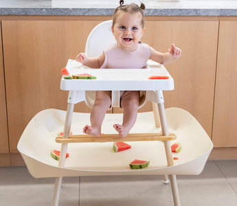 Baby eating watermelon in high chair with mess-catching tray, food-safe and easy clean design