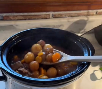 Crock-Pot slow cooker with hearty stew, carrots, and potatoes on kitchen counter