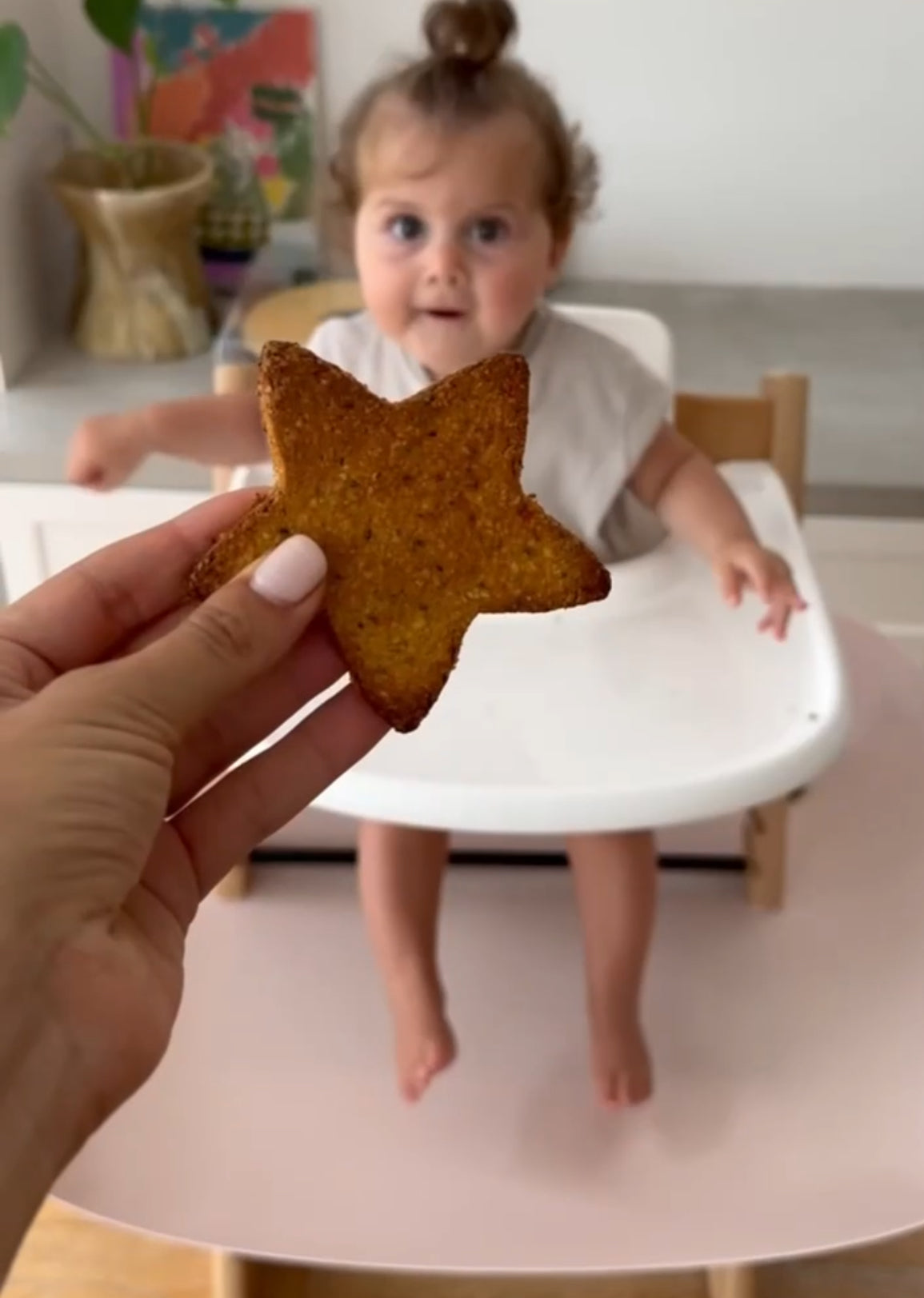 Star-shaped toast offered to baby in high chair, mess-free mealtime solution