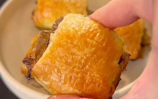 Hand holding golden-brown pastry with flaky crust, perfect for mess-free meals