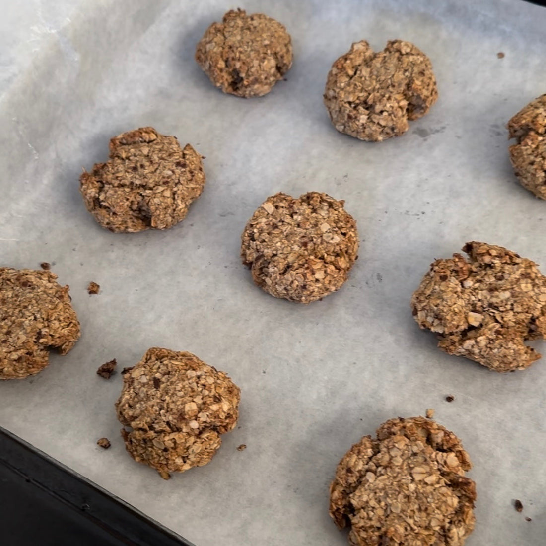 Freshly baked oatmeal cookies on parchment paper, perfect for mess-free snacking with CATCHY.